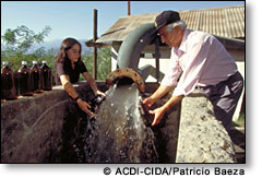 Photo :A man and a woman collect water flowing from a pipe   ACDI-CIDA/Patricio Baeza