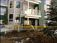 Police tape blocks access to a trench by an apartment complex, where two workers were buried for hours.