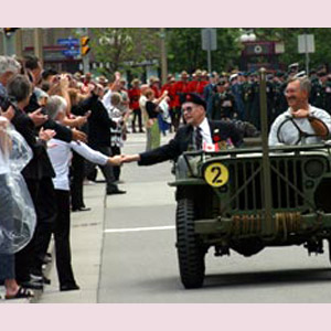 Circulant dans un véhicule militaire d'époque, un ancien combattant serre la main d'une des personnes venues assister à la cérémonie visant à commémorer le 60e anniversaire de la Victoire en Extrême-Orient.