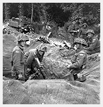 Photo du personnel de tir dun mortier de trois pouces (7,62 cm) de la Compagnie dappui, le Regina Rifle Regiment. Bretteville-lOrgueilleuse, France, vers le 9 juin 1944. Photo prise par le lieutenant Donald I. Grant.