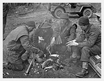 Photo de quatre soldats dinfanterie des Argyll and Sutherland Highlanders of Canada se faisant  manger et se rchauffant autour dun feu dans un enclos de ferme prs de Veen, en Allemagne, 7 mars 1945. Photo prise par le capitaine Jack H. Smith.
