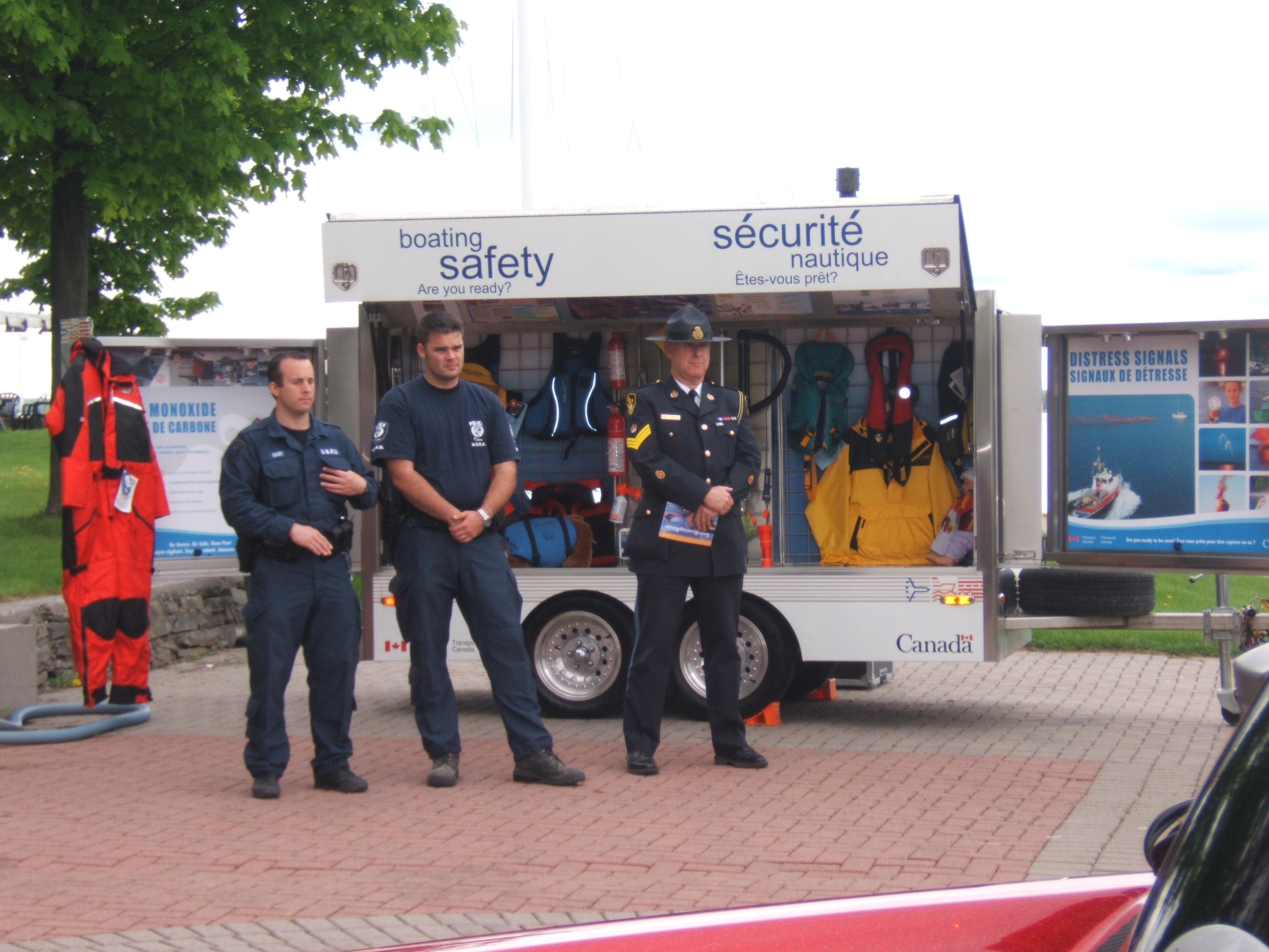 Representatives from the Ottawa Police and the Ontario Provincial Police stand in front of the Office of Boating Safety promotions trailer.