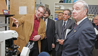 Health researcher Dr. Gerald Zamponi explains his research on new migraine treatments to Prime Minister Paul Martin, University of Calgary President Dr. Harvey Weingarten, Health Minister Ujjal Dosanjh and CIHR President Dr. Alan Bernstein 