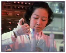 A young woman is using a pipette to drop liquid into a series of test tubes