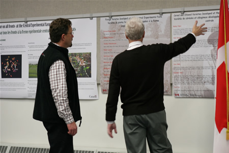 In Ottawa, on November 30th, plant scientist Dr. Malcolm Morrison shows Agriculture and Agri-Food Minister Chuck Strahl the list of cereal and forage crop varieties developed at the Central Experimental Farm during the past 100 years.