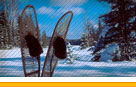 Photo of a pair of crossed snowshoes in a snow bank.