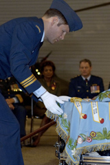 Major Chris Ashton, a pilot with 412 (T) Squadron, tenderly drapes the new colours over the drums during the consecration ceremony.