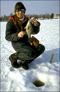an angler displays her catch, while enjoying a day of ice fishing