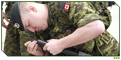 Corporal Cathan Perry checks the butt of his C7 rifle to remove a cleaning kit. 