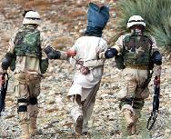 American soldiers escort an Afghan detainee after flex-cuffing and blindfolding him.
