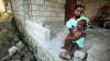 Majnolita Louisome holds her brother Iverson outside their damaged home in Port-au-Prince.