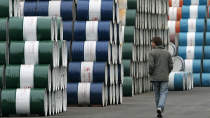 A man walks past a storage area for oil barrels in Shanghai