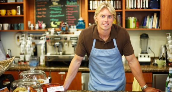 Photo – Man standing behind a counter, wearing an apron