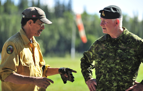 Un membre du Wildland Fire Management du Yukon, et Son Excellence David Johnston, le gouverneur général du Canada, discutent des incendies de forêt qui sévissent dans la région durant l'Opération Nanook 2013, à Carmacks, au Yukon, le 6 août 2013.