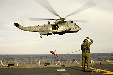 HS2007-J001-090 21 Nov 07 Operation ALTAIR  Sgt Harold Alain signals to the pilot during a basket rescue procedure on the flight deck on HMCS CHARLOTTOWN.  Algonquin, as well as HMC Ships Protecteur, Vancouver, and Ottawa, each had turns practicing firing their main guns at precisely-located targets ashore.  The practice will further enhance their ability to defend themselves against military or non-military threats, allowing warships to stay on station and on task if they come under fire from shore.   The four Canadian ships, with HMCS Calgary, sailed from Victoria, B.C. on Oct. 22 for an exercise to practice core naval warfare skills such as anti-submarine warfare, anti-air and anti-ship defence, as well as naval fire support.  To maximize realistic warfare scenarios, the naval task group joined the USS Abraham Lincoln Carrier Strike Group in the Southern California operating areas.  Calgary integrated with the carrier strike group, who then assumed the role of "friendly force".  The remaining four Canadian ships formed a task group and became the "opposing force".  At specified periods and under pre-scripted conditions, the two forces hunted for each other by sea and air over vast ocean operating areas, simulating complex, multi-threat “kinetic engagements” upon discovery.  The coalition exercise enhances inter-naval operability and provided ship’s crews with valuable training and experience in a multi-national setting.  Photo by Corporal Pier-Adam Turcotte, CFB Esquimalt Imaging Services.