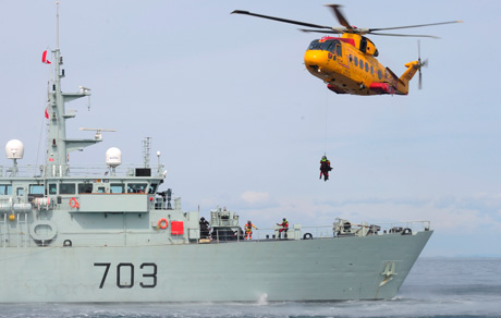 An RCAF CH-149 Cormorant helicopter hovers over the deck of HMCS Edmonton.