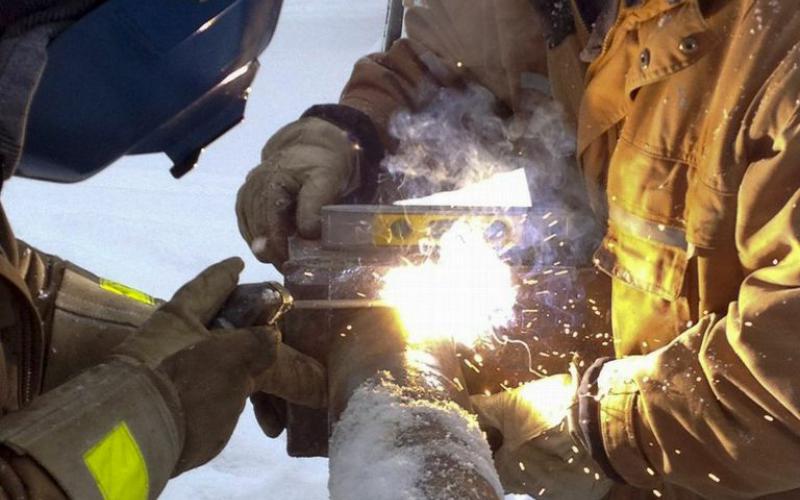 Photo - Welders work on pipe outside as Inuvik’s new Children First Centre is being constructed.