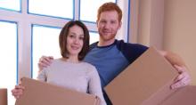 Photo - Young couple holding boxes moving into their new home