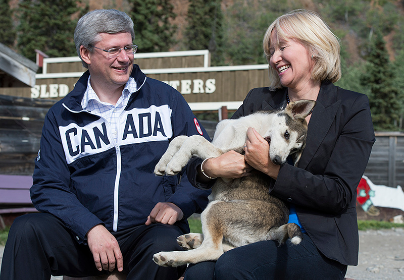 Le Premier ministre Stephen Harper et son pouse, Laureen, jouent avec des chiots alaskan husky qui sont entrans pour devenir des chiens de traneau lors de la premire journe de la tourne annuelle du Premier ministre dans le Nord. Le 20 aot 2012. (Photo par Jason Ransom)