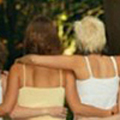 Photograph of the backs of five woman with their arms across each other's shoulders