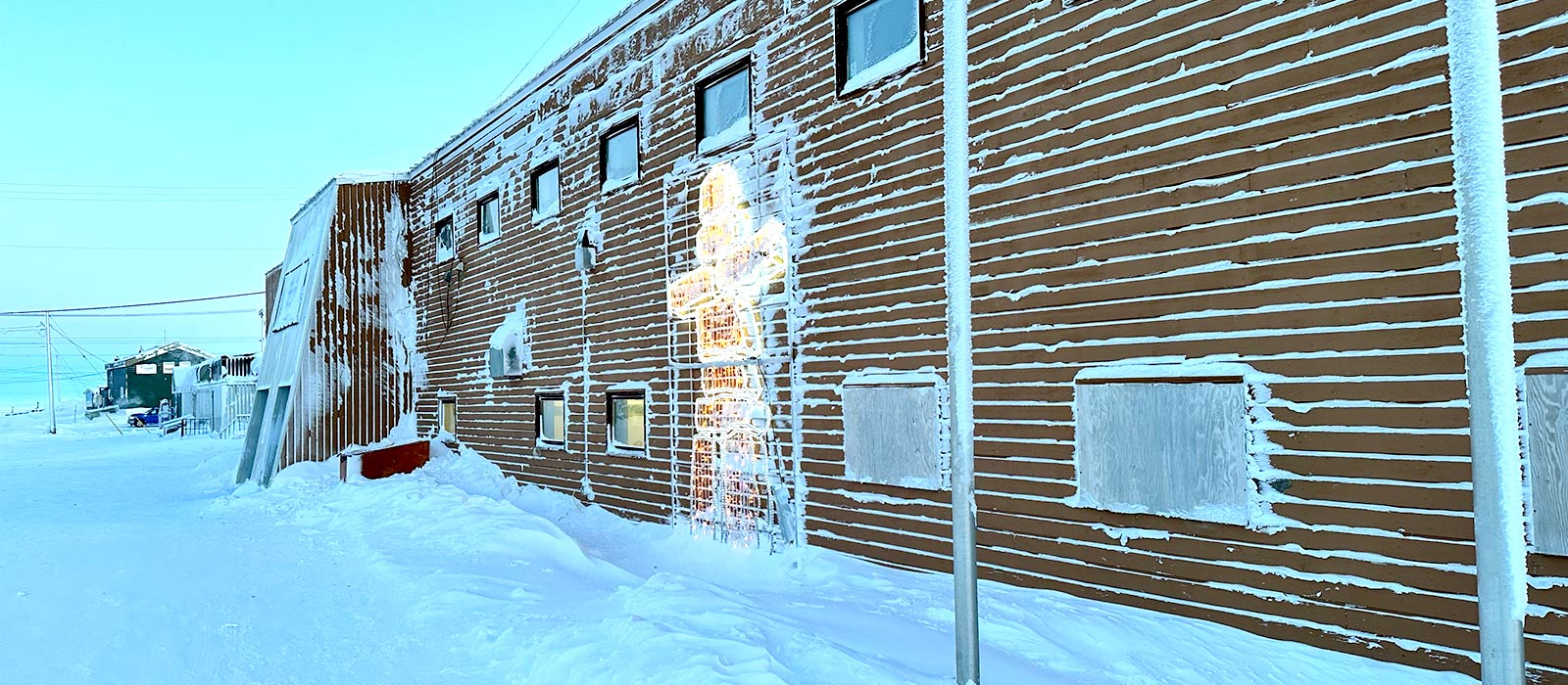 The side of a brick building with snow on the ground.